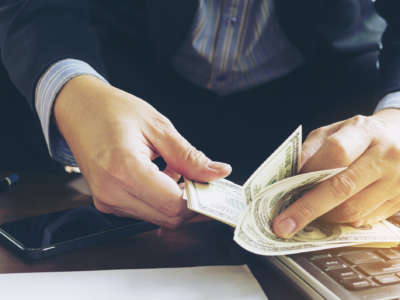 A man counts money at a computer desk