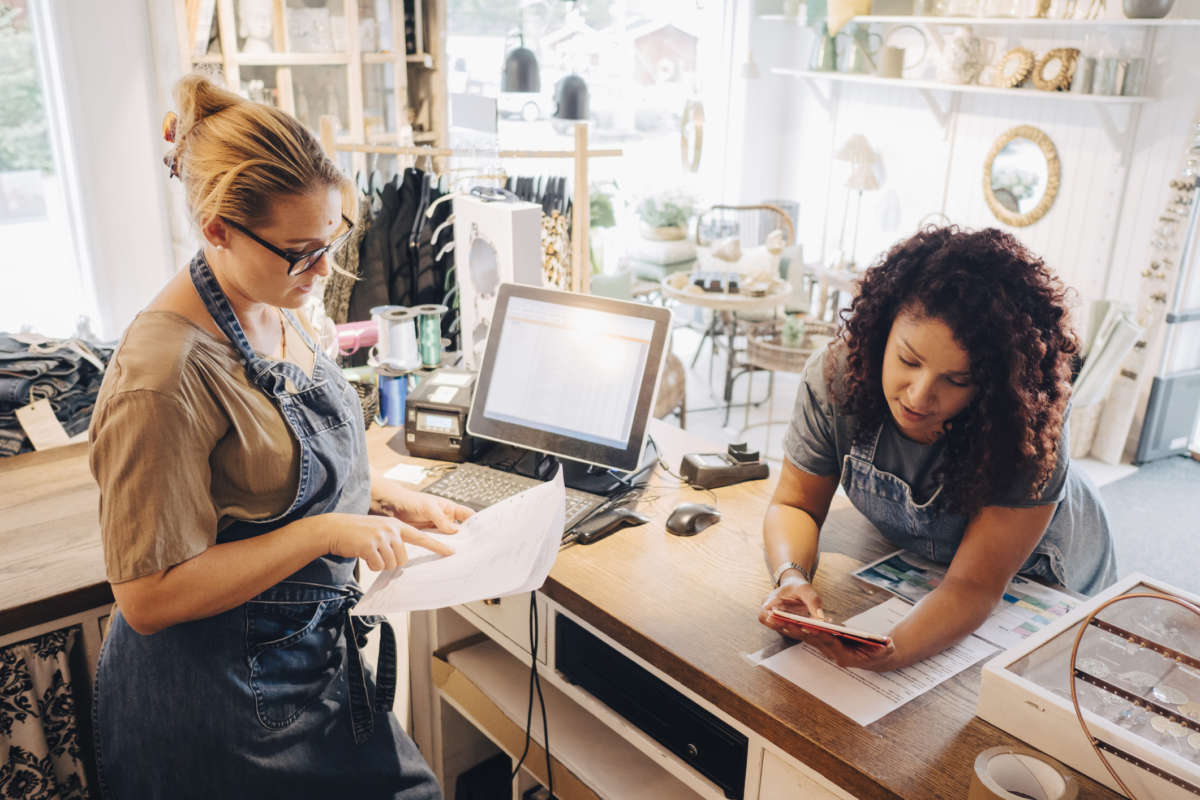 Two women lean over a desk in a small business