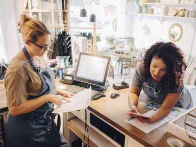 Two women lean over a desk in a small business