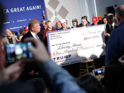 Then-candidate Donald Trump presents a check for $100,000 to the Liberty House during a town hall at the Lions Club February 8, 2016, in Londonderry, New Hampshire.