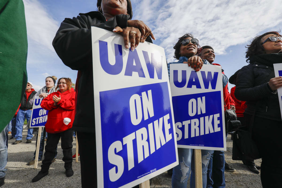 People stand holding signs reading "UAW WORKERS ON STRIKE"