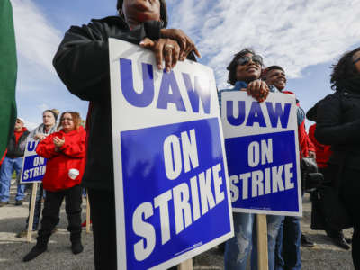 People stand holding signs reading "UAW WORKERS ON STRIKE"