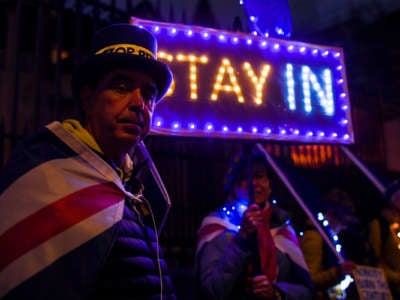 Pro-EU protesters stand in front of a sign opposing the brexit deal