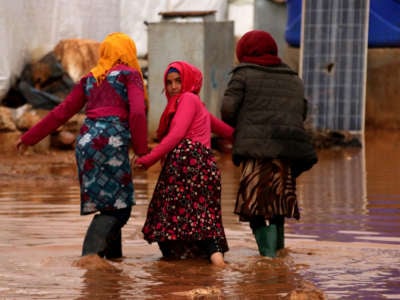 Youths wade through submerged tents at refugee camps after heavy rain hit the Sermada district of Idlib, Syria, on December 5, 2019.