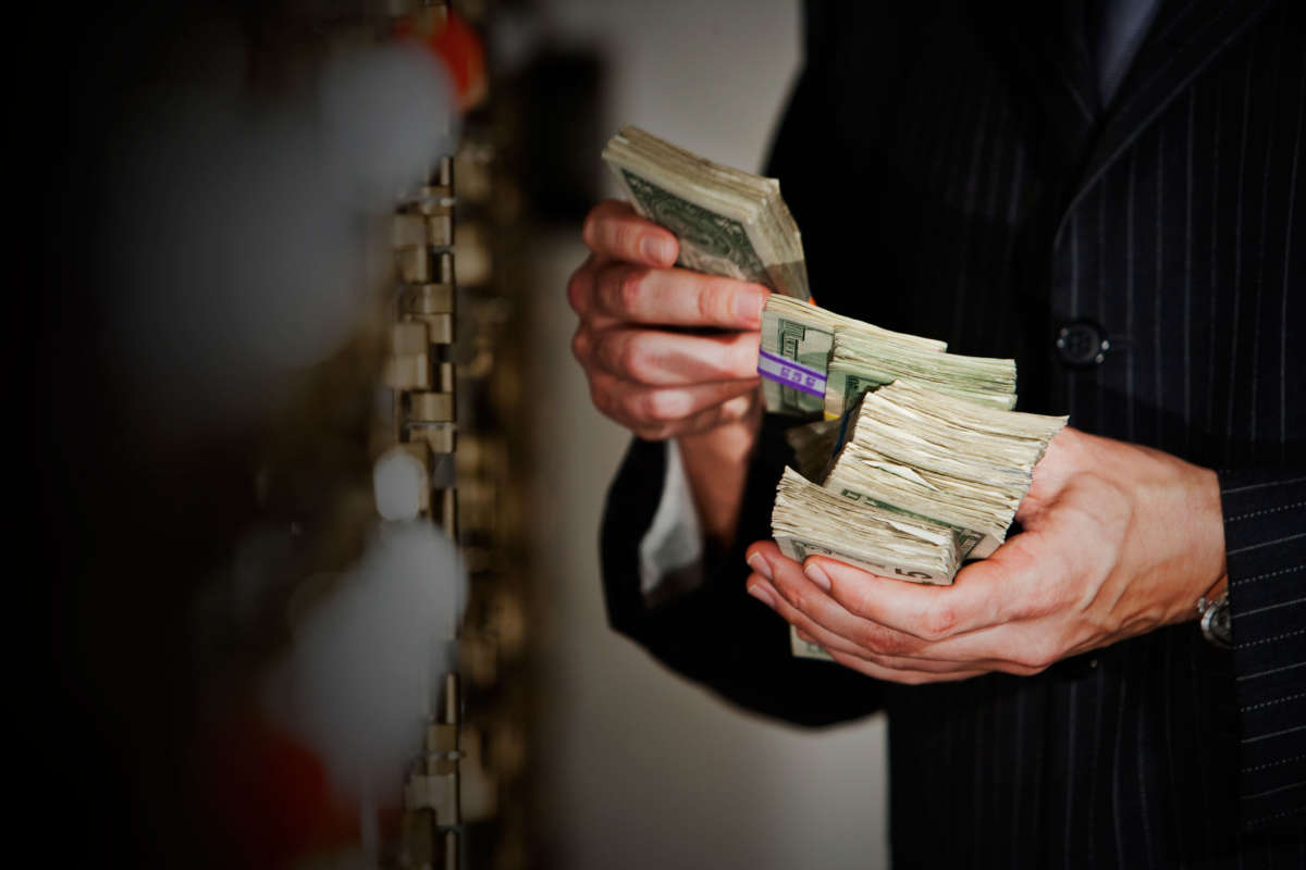 A man counts stacks of money outside of a bank vault