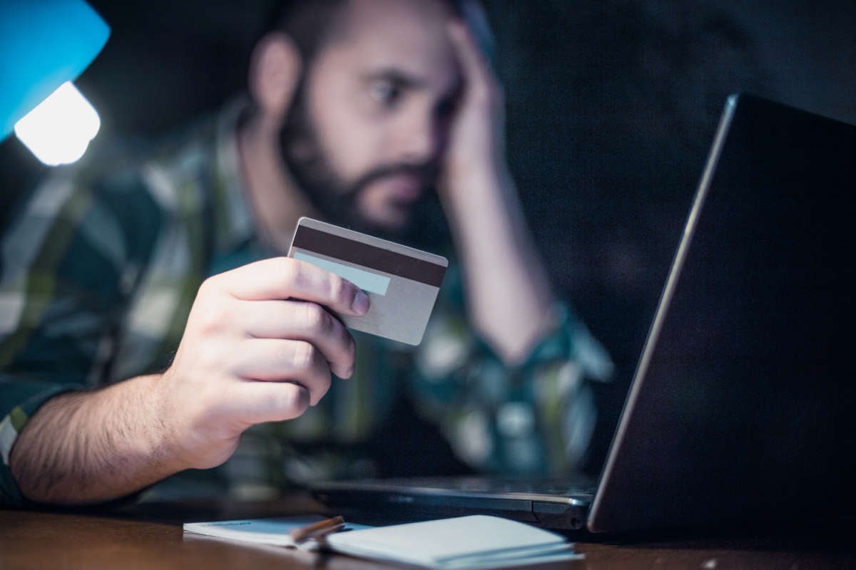 A man looks at his computer screen while holding a credit card