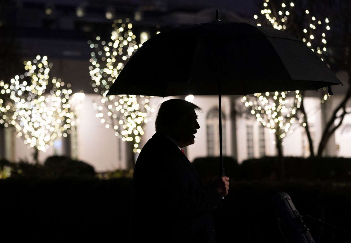 President Trump is seen in silhouette holding an umbrella as he talks to members of the press on the South Lawn of the White House, December 10, 2019.