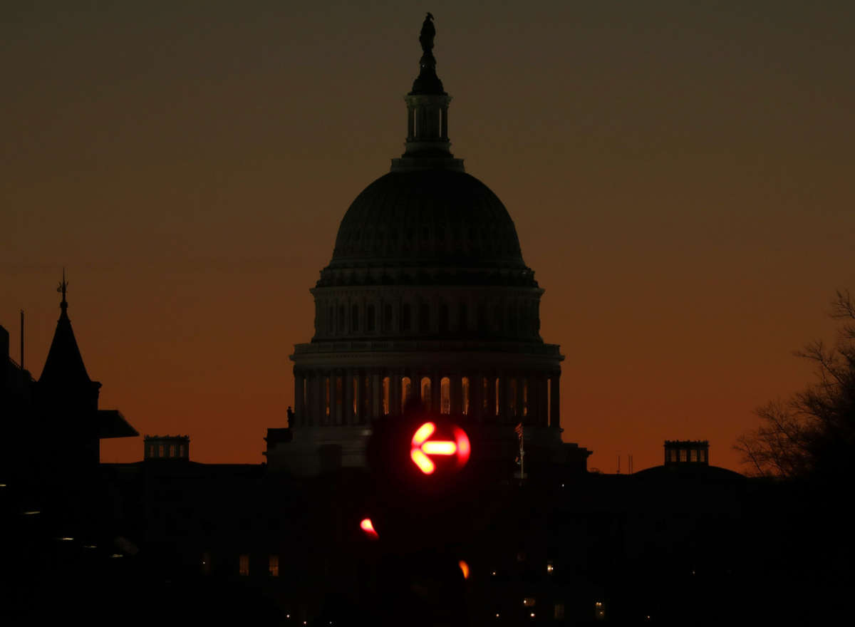 A darkened capitol sits against the setting sun as a red "NO RIGHT TURN" arrow is illuminated in the foreground