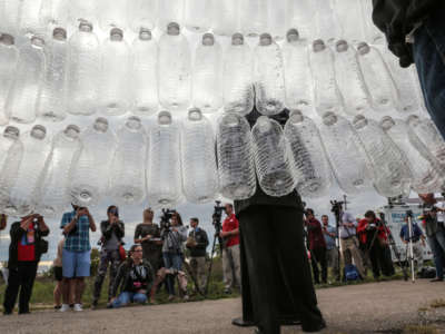 A speaker stands in front of a wall of empty plastic water bottes