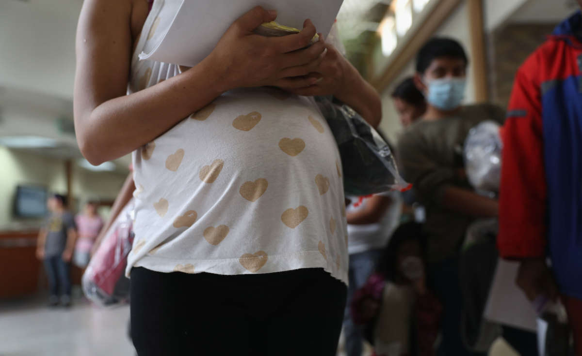 A pregnant Honduran immigrant stands in line with fellow immigrants for a bus to a U.S. destination on August 15, 2016, from McAllen, Texas.