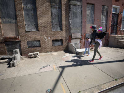 A woman walks with her two daughters through the Upton neighborhood of Baltimore, Maryland, on April 3, 2019. Life expectancy in Upton is 68.2 years, while the average for the city is 73.6, according to Baltimore City data from 2017.