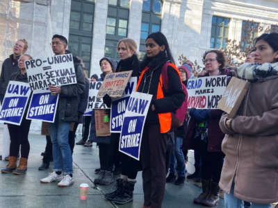 activists hold signs reading "UAW ON STRIKE"