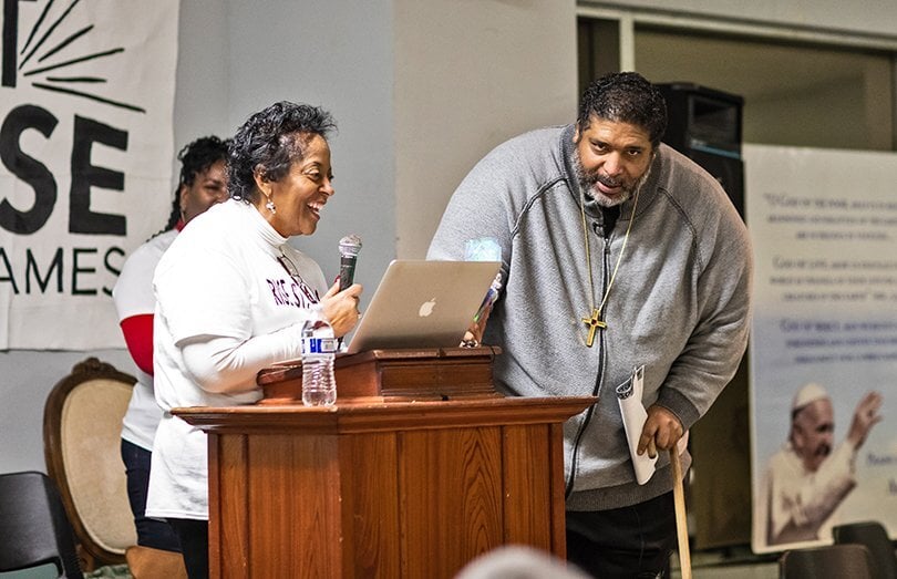 Sharon Lavigne speaks into a microphone at a podium as Rev. William Barber stands nearby