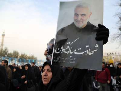 A woman holds a photo of Qasem Soleimani during a demonstration