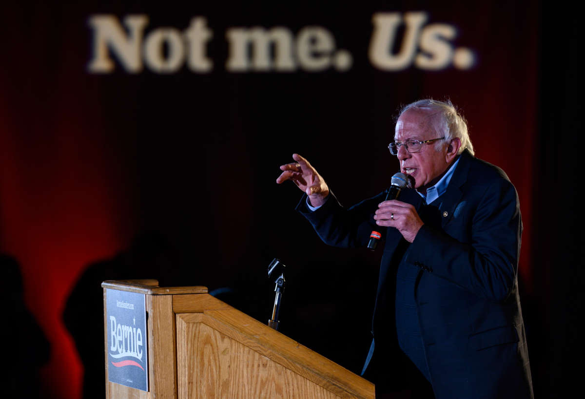 Bernie Sanders speaks into a microphone while standing at a podium