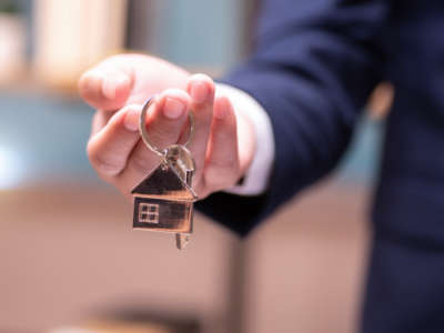 A man offers a key with a house-shaped keychain attached