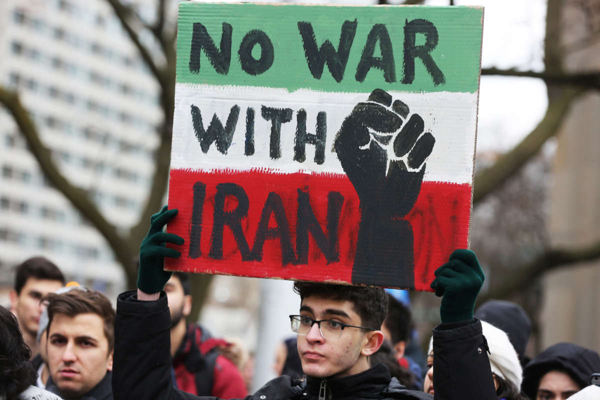 A protester holds a sign reading "No War with Iran" as