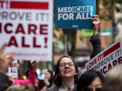 A protester holds a sign supporting medicare for all