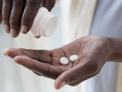 A woman pours two pills into her hands from a bottle