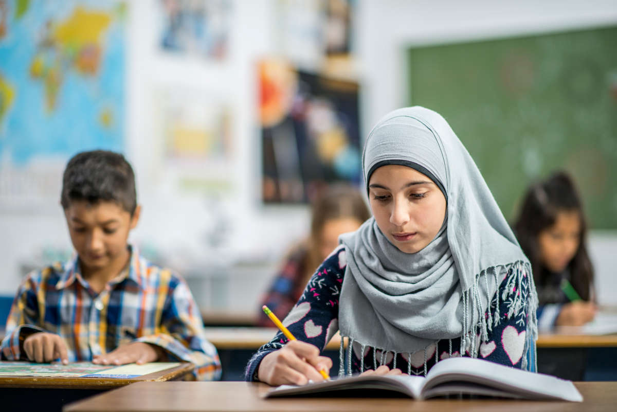 A girl in a hijab works on an assignment in school