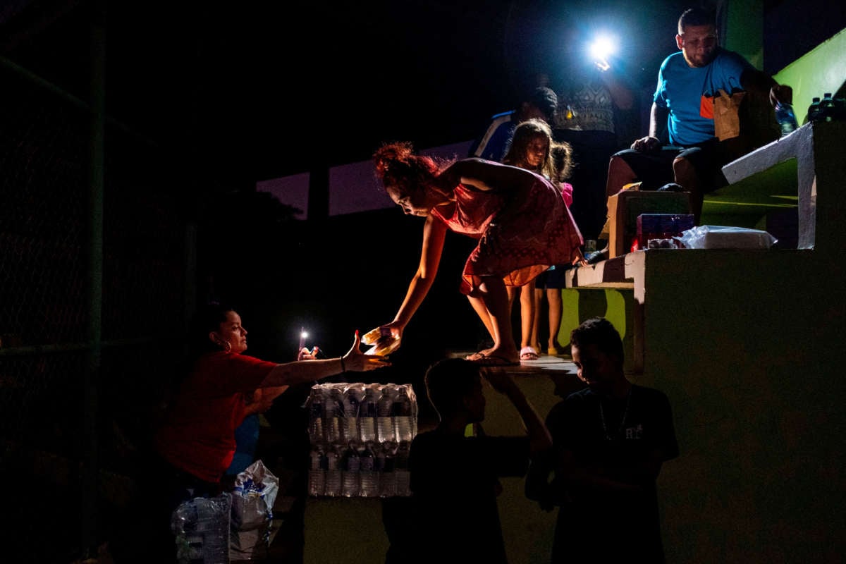 People share food and water on a baseball field where they are sleeping outdoors in Guanica, Puerto Rico on January 9, 2020, after a powerful earthquake hit the island.