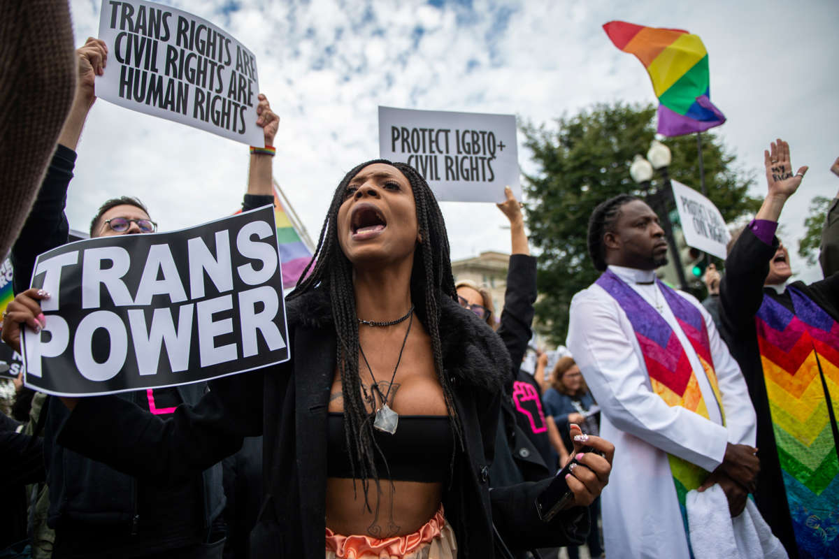 A woman holds a sign reading "TRANS POWER" during an protest