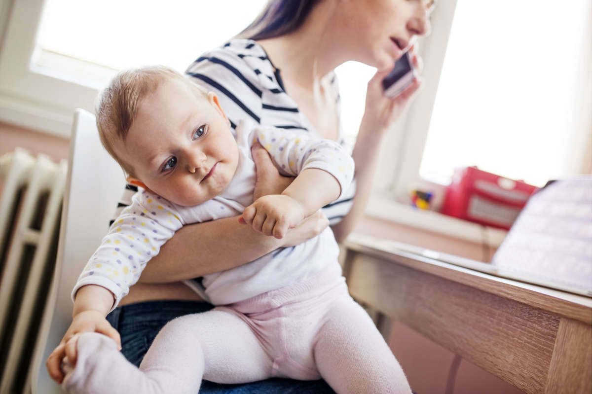 Mother carrying baby while on phone