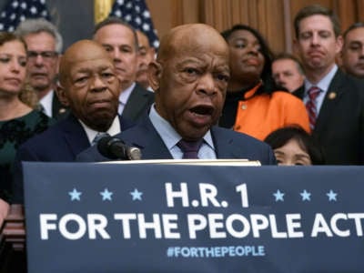 Rep. John Lewis speaks at a podium surrounded by other democrats