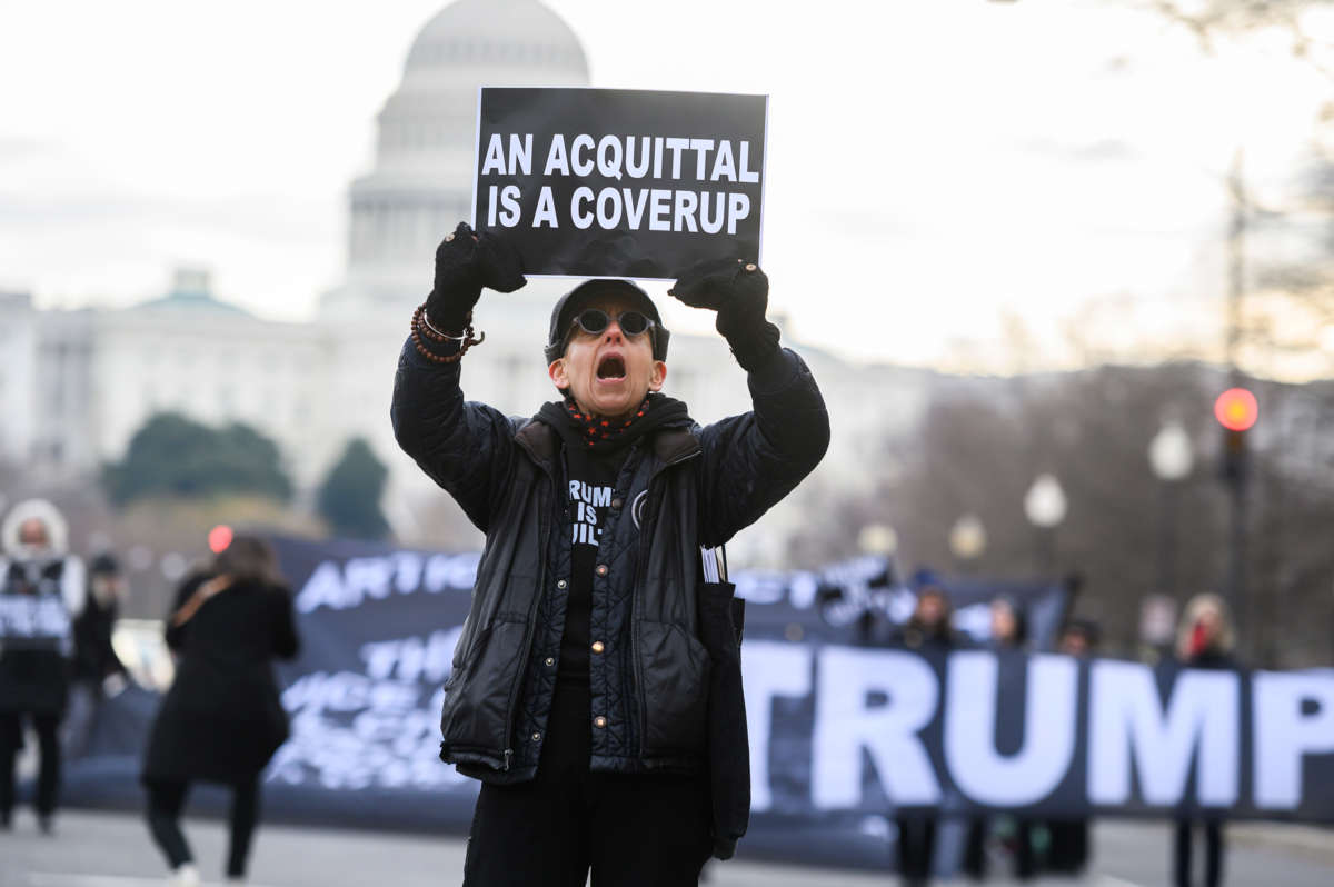 A protester holds up a sign reading "AN ACQUITAL IS A COVERUP" while joining an action in front of the u.s. capitol