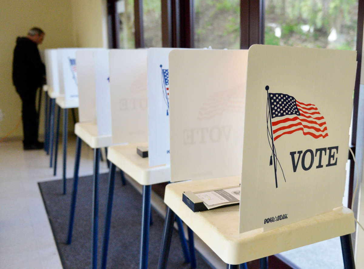 A person votes at a row of voting booths