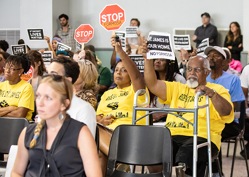 People in yellow shirts raise signs in protest