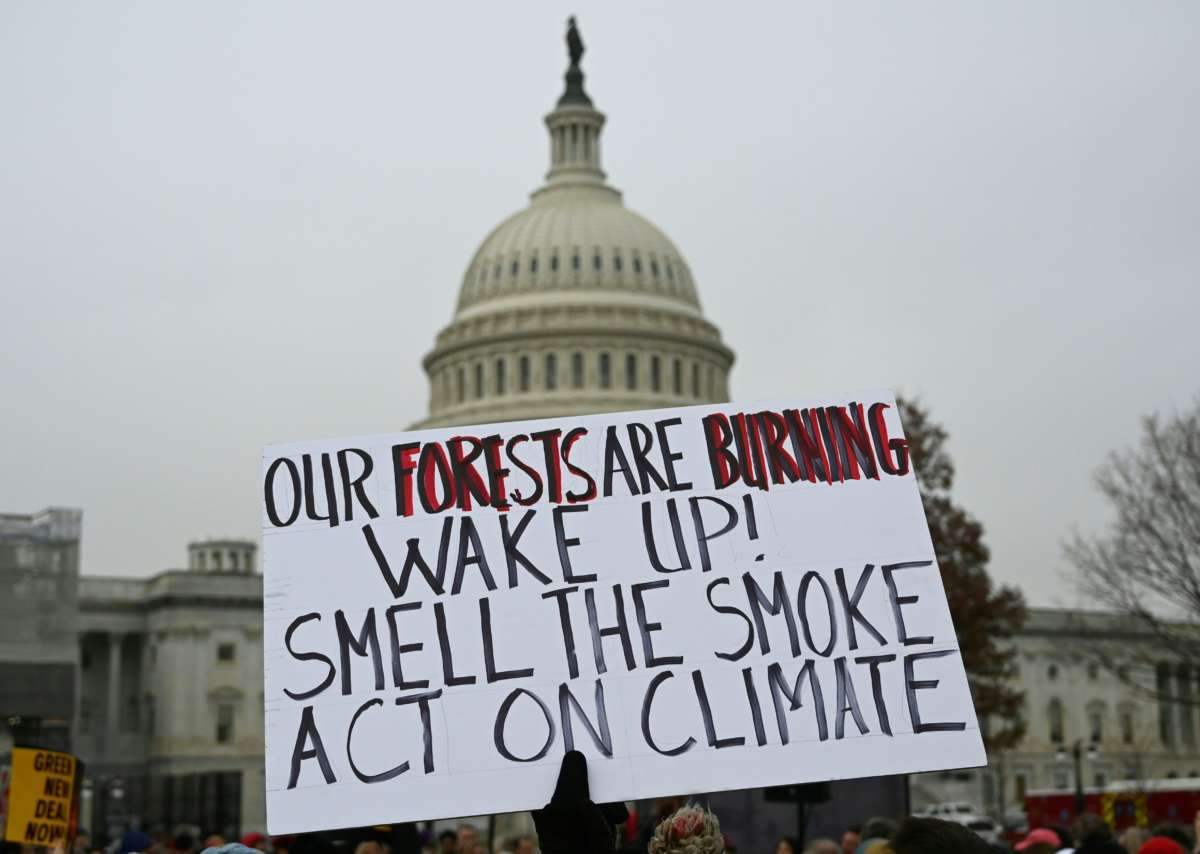 A person hoists a poster in front of the U.S. Capitol during climate protest in Washington, D.C., on December 27, 2019.