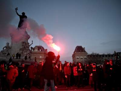 Protesters light flares during a demonstration in Paris, on January 11, 2020, as part of a nationwide multi-sector strike against the French government's pensions overhaul.