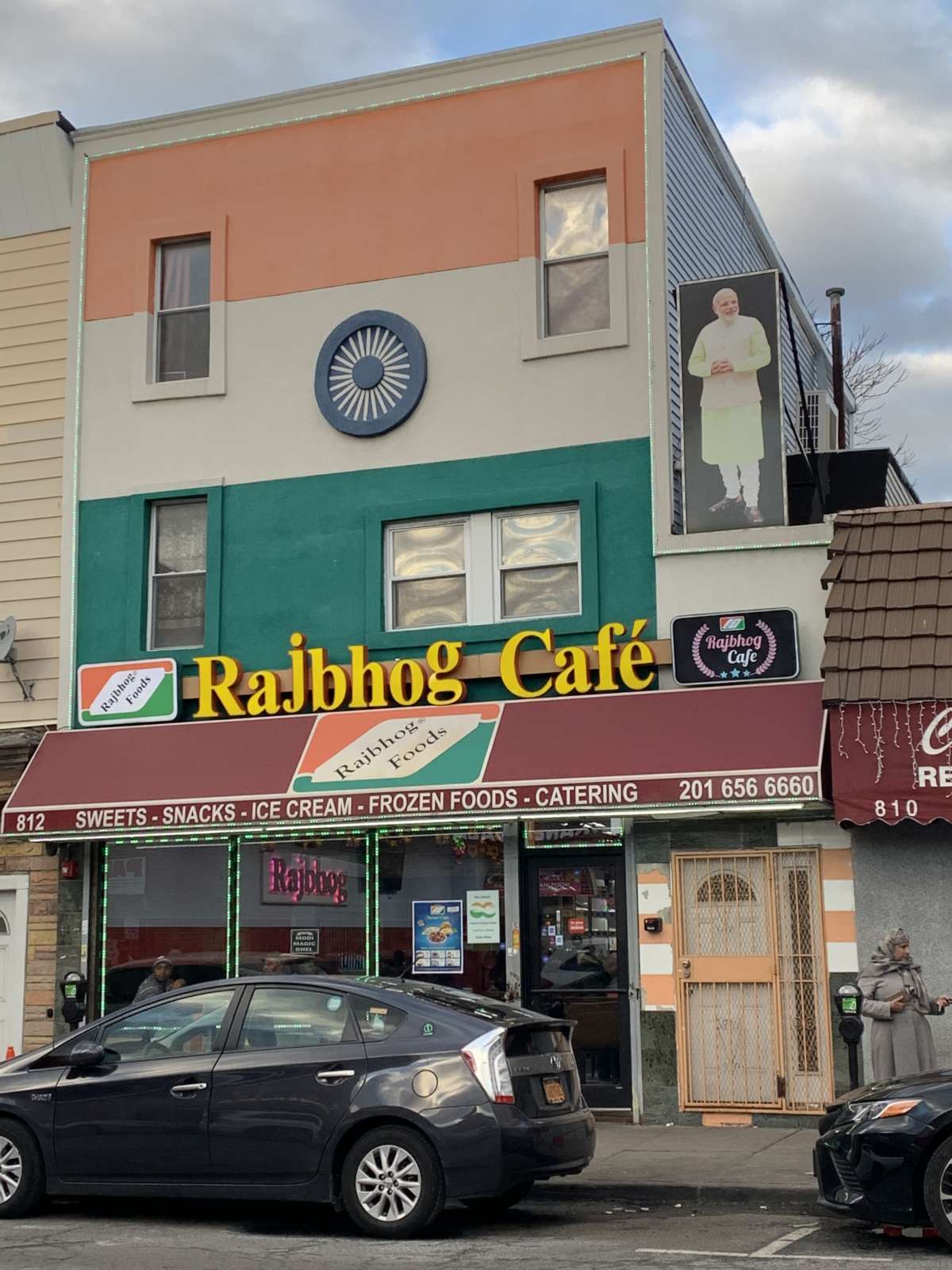 Rajbhog Cafe on Newark Avenue, Jersey City, NJ, where a large picture of a picture of Narendra Modi is hung above.