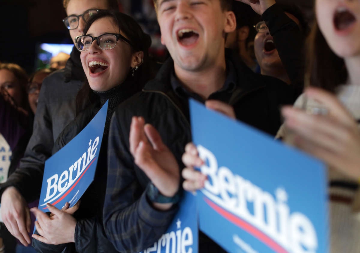 Fans of Sen. Bernie Sanders cheer while holding his sineage
