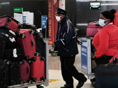 Airport workers wear face masks as they handle luggage