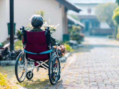 A person sits in a wheelchair outside