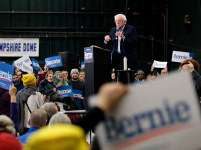 Bernie Sanders speaks at a podium to a crowd of his supporters during a campaign rally