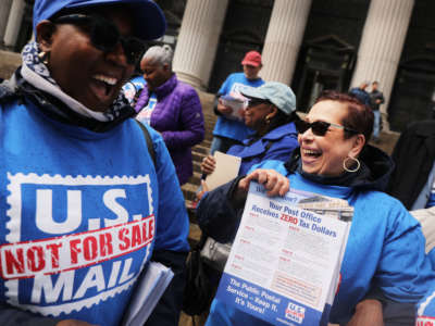 USPS workers cheer during a protest