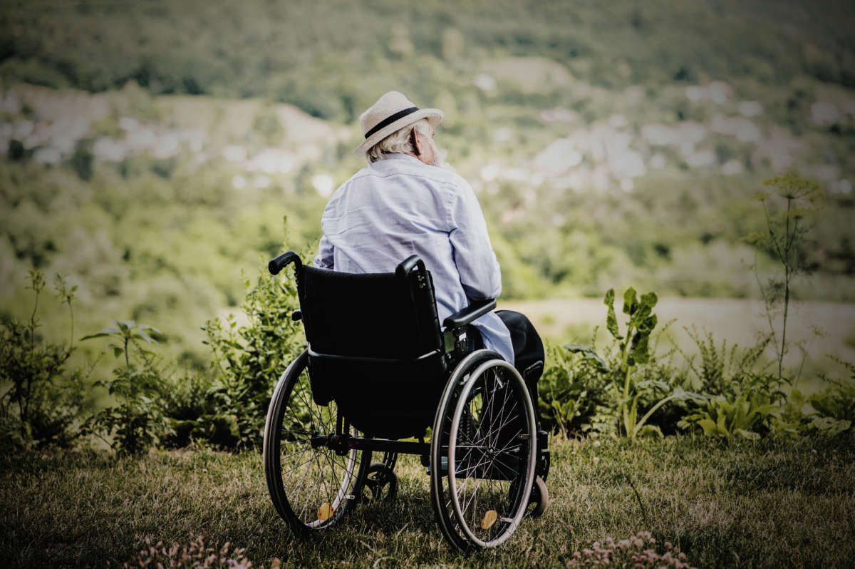 An elderly man sits in a wheelchair
