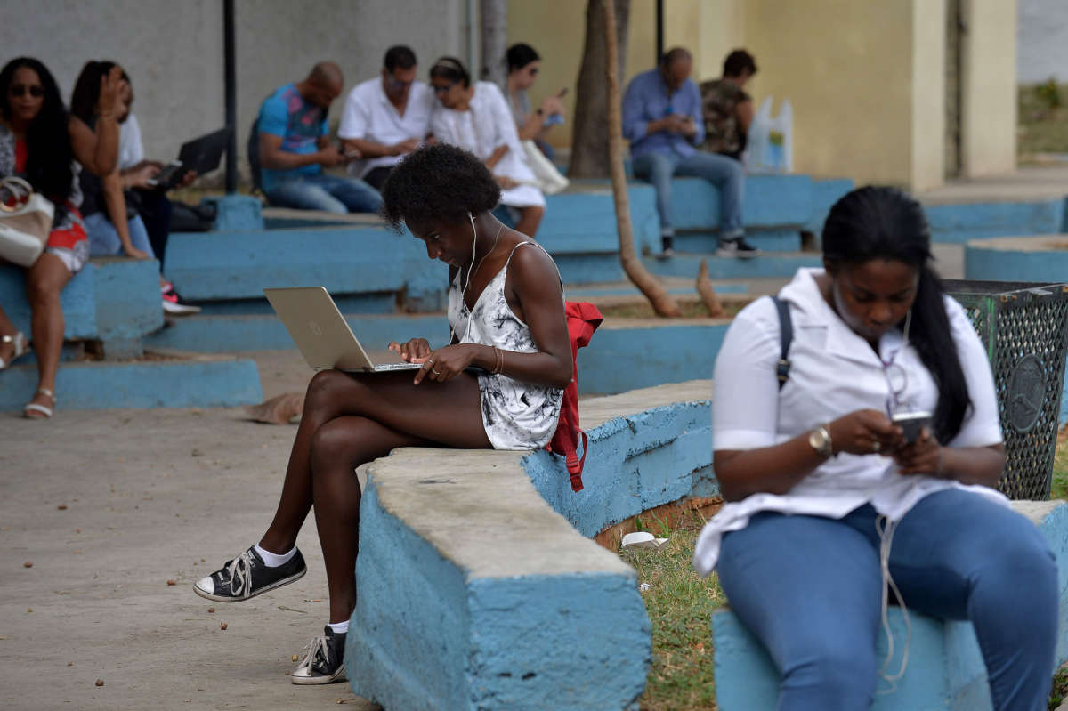 People use their mobile phones and laptops to connect to the internet at a park in Havana, Cuba, on December 5, 2018.