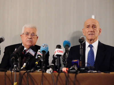 Palestinian president Mahmud Abbas and Former Israeli Prime Minister Ehud Olmert sit at a podium