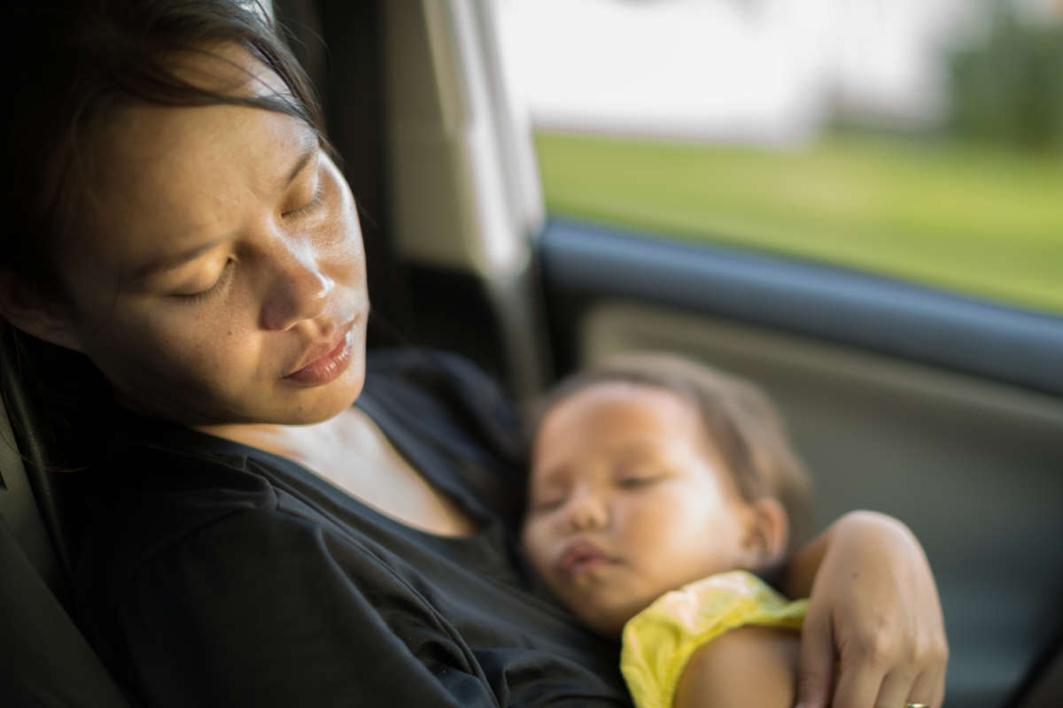 A mother holds her baby in the backseat of a moving car