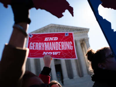 A protester holds a sign reading "END GERRYMANDERING NOW" in front of the US capitol building