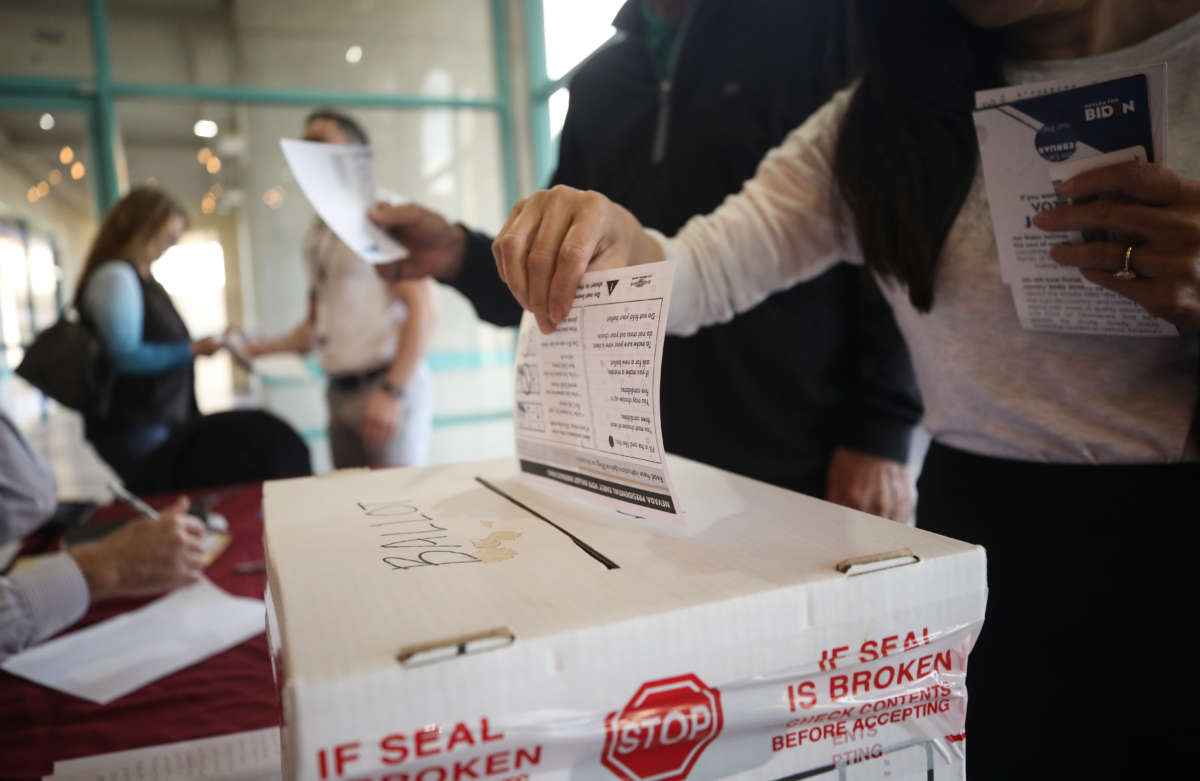 A voter puts a ballot into a ballot box