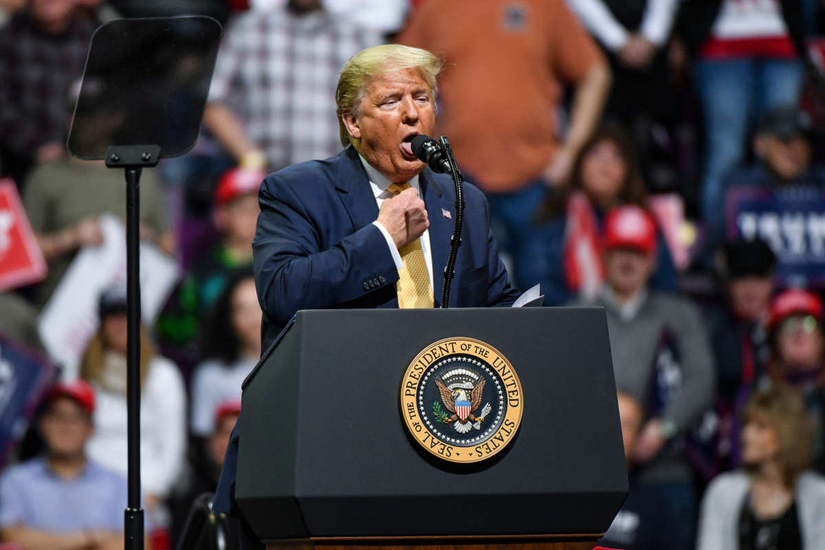 Donald Trump imitates gagging, presumably, while standing at a podium during a rally