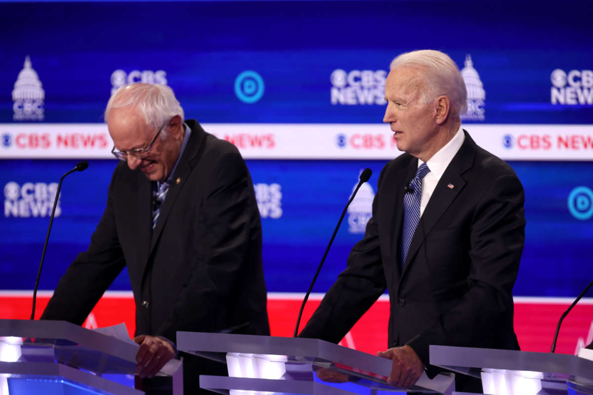 Sen. Bernie Sanders giggles at his podium as Former Vice President Joe Biden speaks