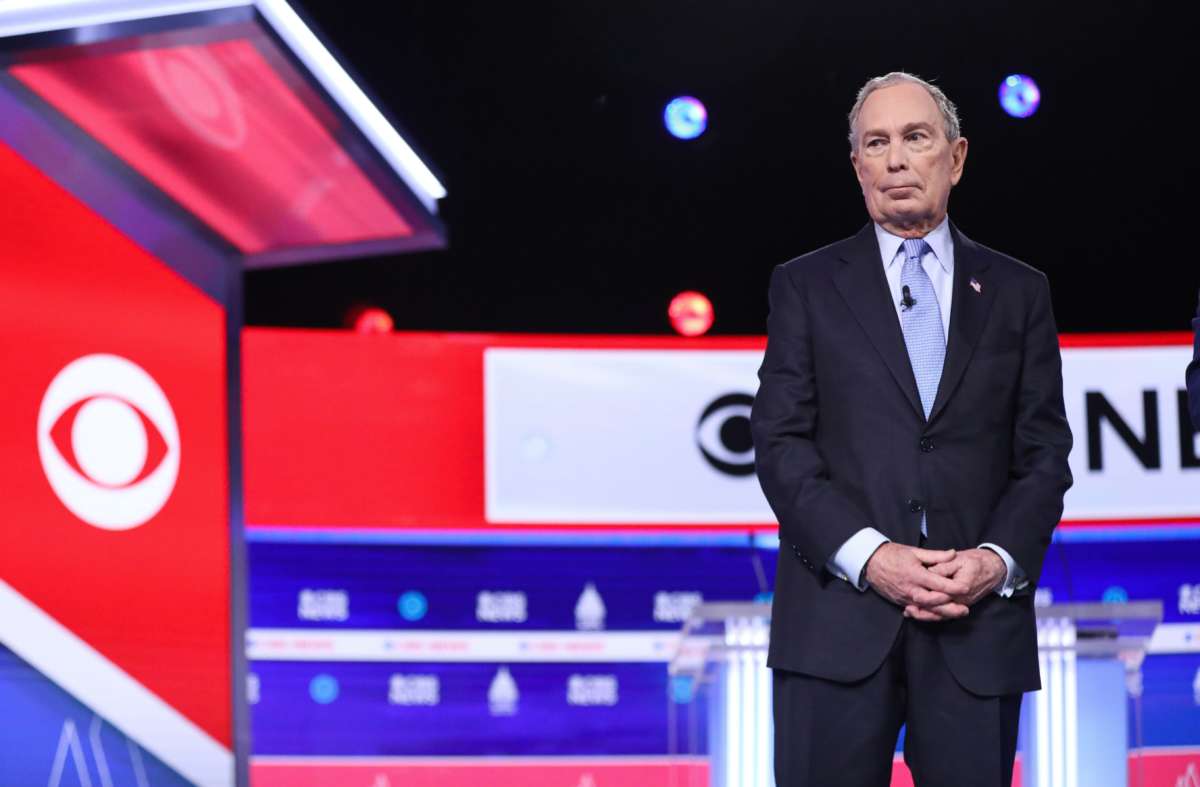 Mike Bloomberg stands to the left of the frame during a debate