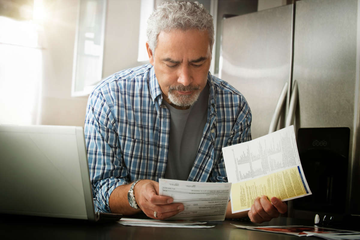 A man looks grumpily at bills in his hand