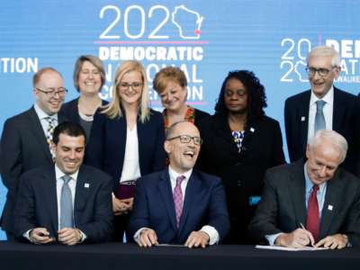 Democratic National Committee members sign a document announcing the selection of Milwaukee as the 2020 Democratic National Convention host city as Wisconsin Governor Tony Evers and DNC Chair Tom Perez look on during a press conference at the Fiserv Forum in Milwaukee, Wisconsin, on March 11, 2019.